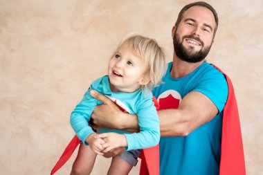 Adam ve çocuk süper kahraman evde. Süper kahraman baba ve oğul birlikte eğleniyor. Aile tatil kavramı. Mutlu babalar günü