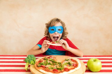 Süper kahraman çocuk superfood yeme. Mutlu bir çocukluk evde yemek yiyor. Sağlıklı beslenme ve yaşam tarzı kavramı. Yeşil vejetaryen yemek