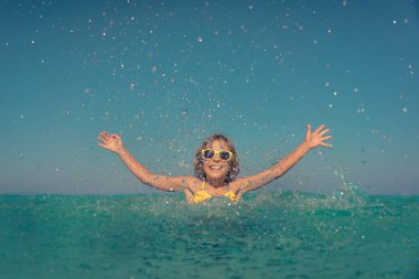 Denizde oynayan mutlu çocuk. Çocuk yaz tatile eğleniyor. Sağlıklı aktif yaşam tarzı kavramı