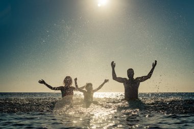 Denizde mutlu bir aile. Çocuk, anne ve baba yaz tatile eğleniyor. Sağlıklı aktif yaşam tarzı kavramı