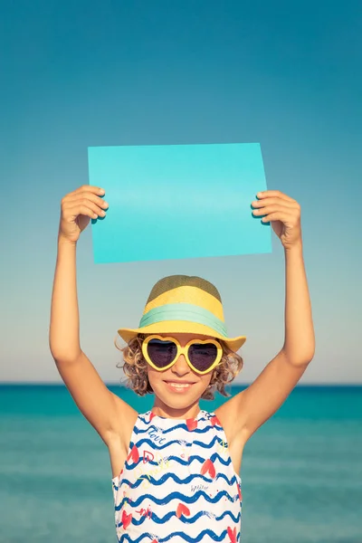 幸せな子供は 海と空の背景に対して空白の紙を保持しています 子供の夏休みに楽しい時を過します 健康的なアクティブなライフ スタイル コンセプト — ストック写真