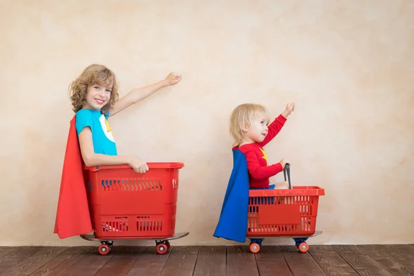 Crianças felizes dirigindo carro de brinquedo em casa — Fotografia de Stock