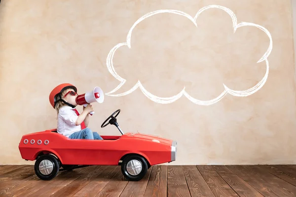 Divertido niño conduciendo coche de juguete en casa — Foto de Stock