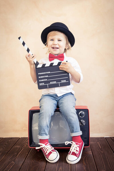 Child with clapper board playing at home.