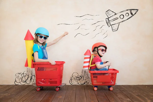 Niños divertidos conduciendo coche de juguete interior —  Fotos de Stock