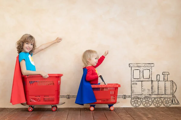 Niños divertidos conduciendo coche de juguete interior — Foto de Stock