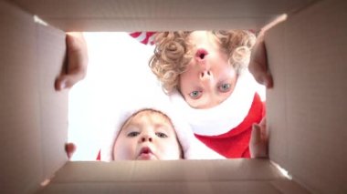 Mutlu çocuklar kutuya bakıyor. Komik sürpriz çocuklar Noel hediye kutusunu açmak. Xmas tatil konsepti. Düşük açı görünümü. Yavaş çekim 120fps