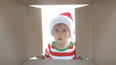 Mutlu çocuk kutuya bakıyor. Komik sürpriz çocuk Noel hediye kutusu açmak. Xmas tatil konsepti. Düşük açı görünümü. Yavaş çekim