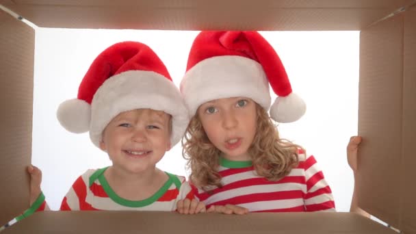 箱の中を見て幸せな子供たち 面白い驚いた子供たちはクリスマスギフトボックスを解凍します エクスマスホリデーコンセプト 低角ビュー スローモーション 120Fps — ストック動画