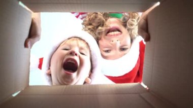 Mutlu çocuklar kutuya bakıyor. Komik sürpriz çocuklar Noel hediye kutusunu açmak. Xmas tatil konsepti. Düşük açı görünümü. Yavaş çekim 120fps