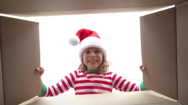Mutlu çocuk kutuya bakıyor. Komik sürpriz kız Noel hediye kutusu açmak. Xmas tatil konsepti. Düşük açı görünümü. Yavaş çekim