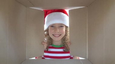Mutlu çocuk kutuya bakıyor. Komik sürpriz kız Noel hediye kutusu açmak. Xmas tatil konsepti. Düşük açı görünümü. Yavaş çekim