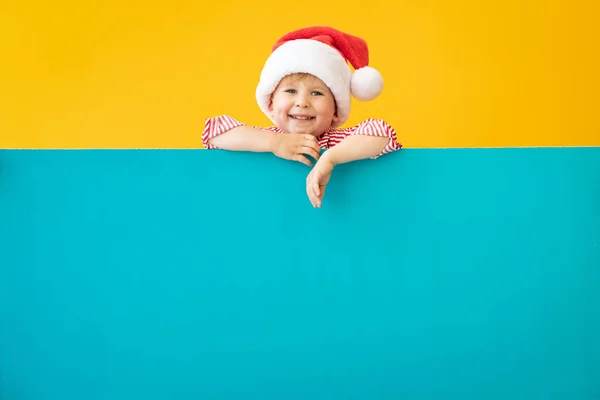Criança feliz segurando azul banner de Natal em branco contra b amarelo — Fotografia de Stock