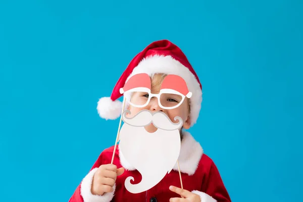 Śmieszne dziecko ubrane strój Świętego Mikołaja na niebieskim tle — Zdjęcie stockowe