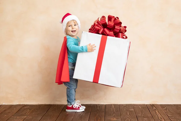 Niño feliz vestido superhéroe celebración de la caja de regalo de Navidad — Foto de Stock