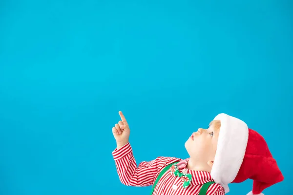 Gelukkig kind gekleed Santa Claus hoed tegen blauwe achtergrond — Stockfoto