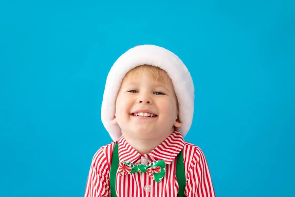 Gelukkig kind gekleed Santa Claus hoed tegen blauwe achtergrond — Stockfoto