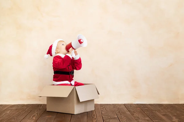 Onnellinen lapsi pukeutunut Joulupukin puku leikkii kotona — kuvapankkivalokuva