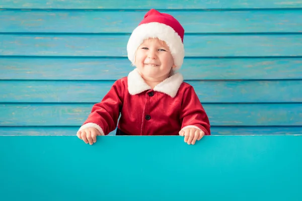 Criança feliz segurando azul banner de Natal em branco contra b de madeira — Fotografia de Stock