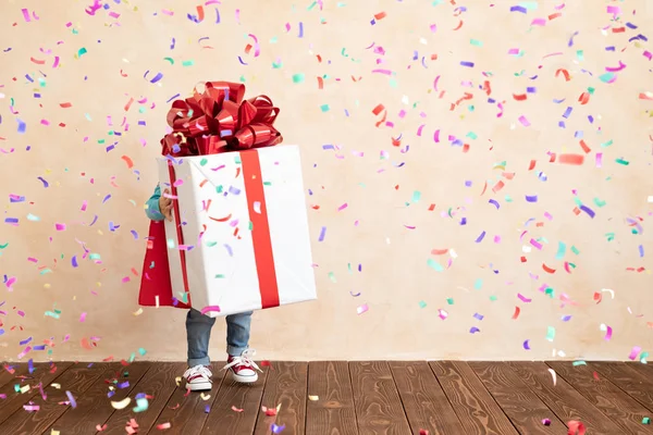 Criança feliz vestido super-herói segurando caixa de presente de Natal — Fotografia de Stock