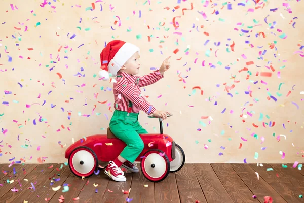 Criança feliz vestindo traje de Papai Noel jogando em casa — Fotografia de Stock