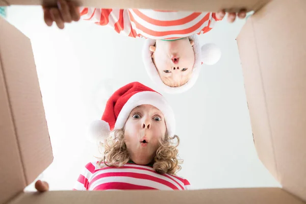 Niños sorprendidos desempaquetan caja de regalo de Navidad —  Fotos de Stock