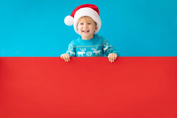 Happy Child Holding röd jul banner blank mot blå tillbaka — Stockfoto
