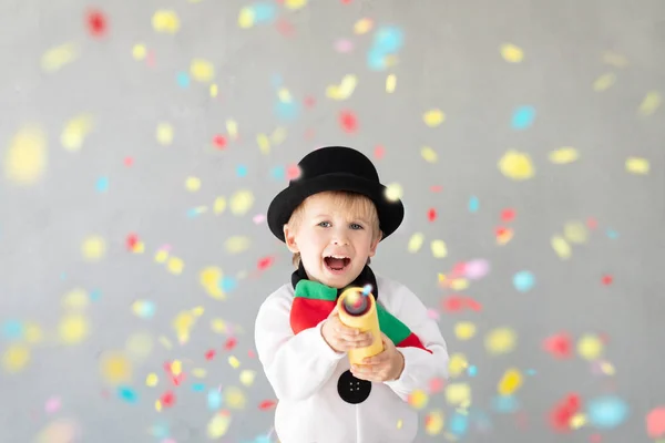 Happy child wearing snowman holding party popper — Stock Photo, Image