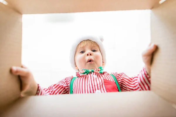 Удивлённый ребёнок распаковывает рождественские подарки — стоковое фото