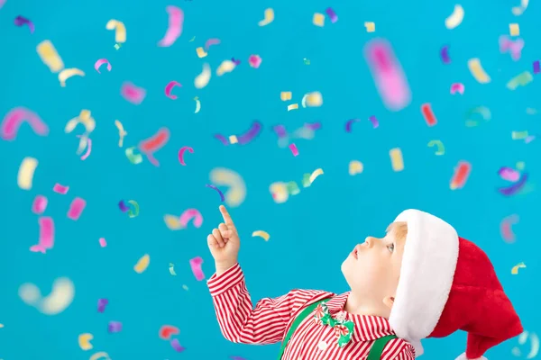 Happy Child klädd jultomten hatt mot blå bakgrund — Stockfoto