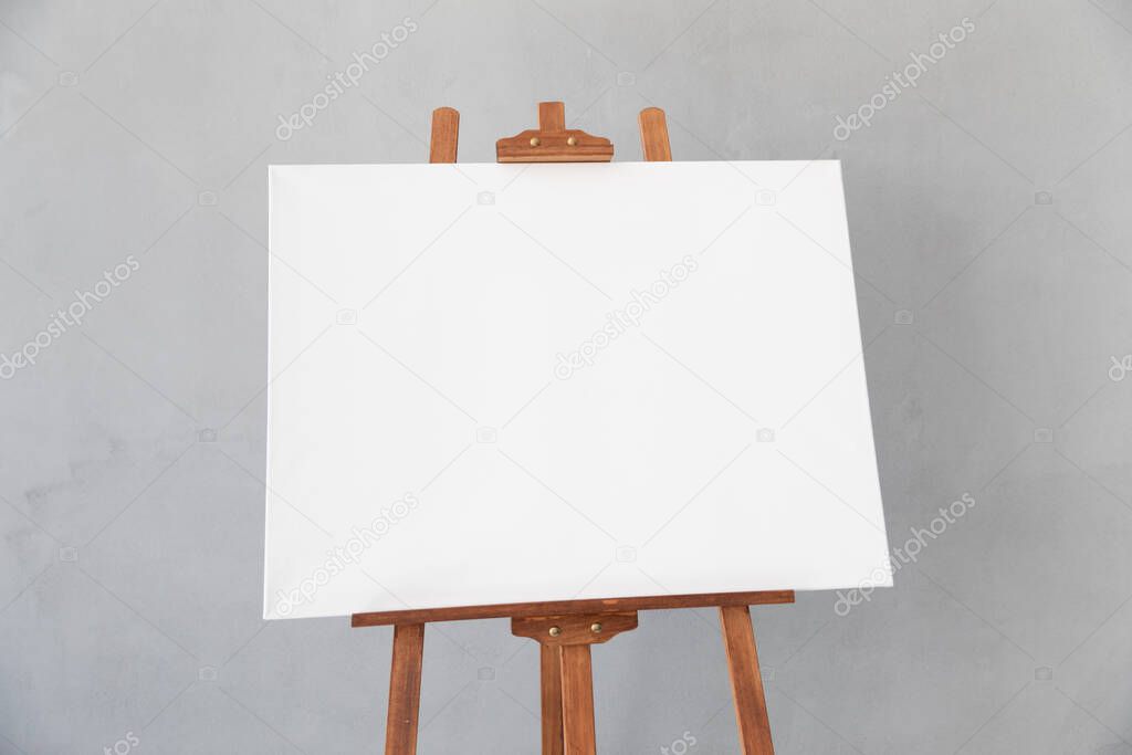 Wooden easel with white canvas blank in studio. Copy space for your text