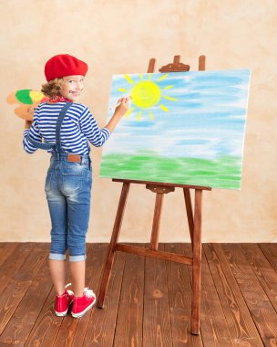 Sanatçı çocuk tabloyu tuvale boyuyor. Mutlu çocuk ressam gibi davranıyor. Hayal gücü ve çocukluk hayali kavramı