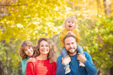 Mutlu aile sonbahar parkında eğleniyor. Çocuklar ve ebeveynler sarı bulanık yapraklara karşı arka plan