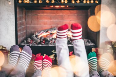 Noel 'de şöminenin yanında çocukları olan mutlu bir aile. Yılbaşı çorabı giyen ayaklar. Kış tatili kavramı
