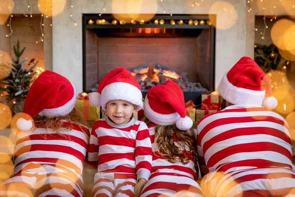 Noel Şöminenin Yanında Çizgili Pijama Giyen Çocuklu Mutlu Bir Aile — Stok fotoğraf