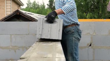 Tuğla ustası bir sıra tuğla daha yerleştiriyor.