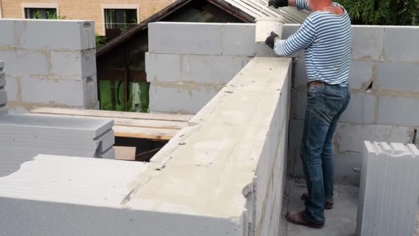 Albañil poniendo otra fila de ladrillos en el sitio — Vídeos de Stock