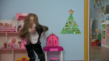 Beyaz beyaz Avrupa küçük kız 5 yaşında uzun saçlı pembe papyon ağır çekimde çocuk odasında ile siyah penguen kostüm ip atlama ile atlama.