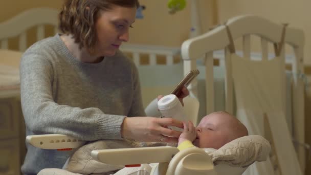 Mor Feeds Baby med telefon — Stockvideo