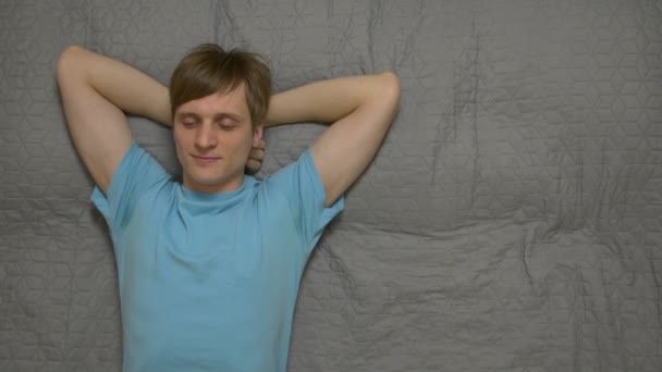 Hombre joven sueña en la cama — Vídeo de stock