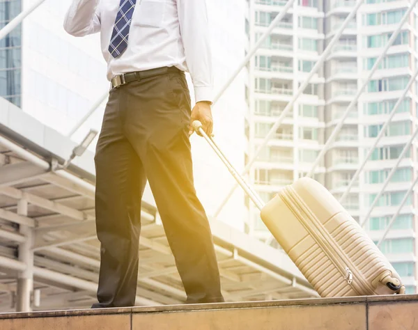 Businessman traveler with luggage at city background