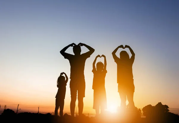 Silhouette baba anne ve iki çocuğu günbatımı, mutlu aile kavramı üzerinde eğleniyor.