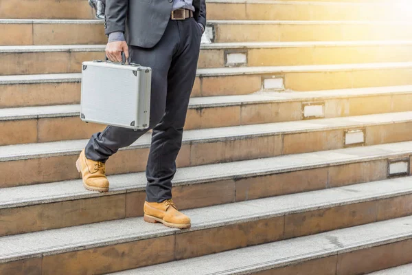 Businessman walking down stairs with bags to office.
