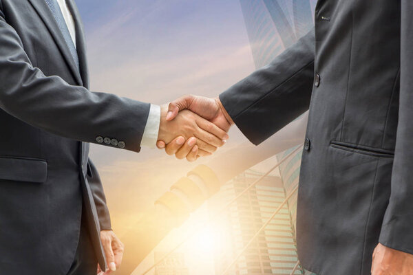Success and Happiness Team Concept Business man handshake, Double exposure photo of city view at sunrise background.