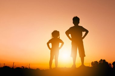 Erkek ve kız günbatımı akşam gökyüzü artalanda çalışır siluetleri.