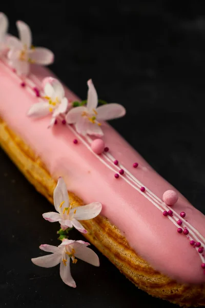 fresh sweet Eclair, pastry. with bright pink strawberry icing and berry filling