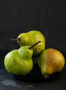 seçici odak: koyu arkaplan üzerinde su damlaları olan büyük olgun armutlar