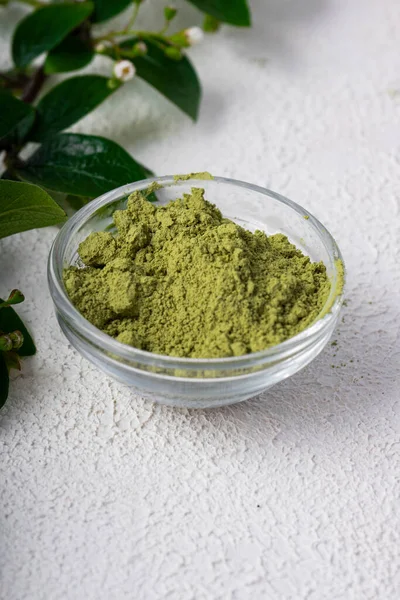 green powder of Chinese matcha tea on a white light background. vertical position