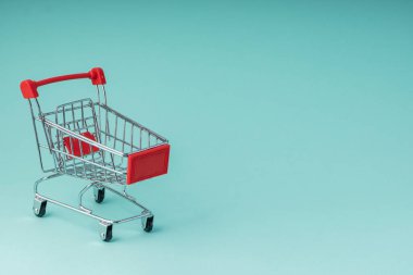 seçici odak, küçük oyuncak market arabası, mavi arkaplanda telif alanı, yatay konum