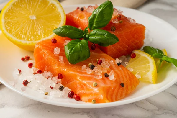 Baharatlı hafif tuzlu alabalık dilimleri, beyaz tabakta fesleğen ve limon.